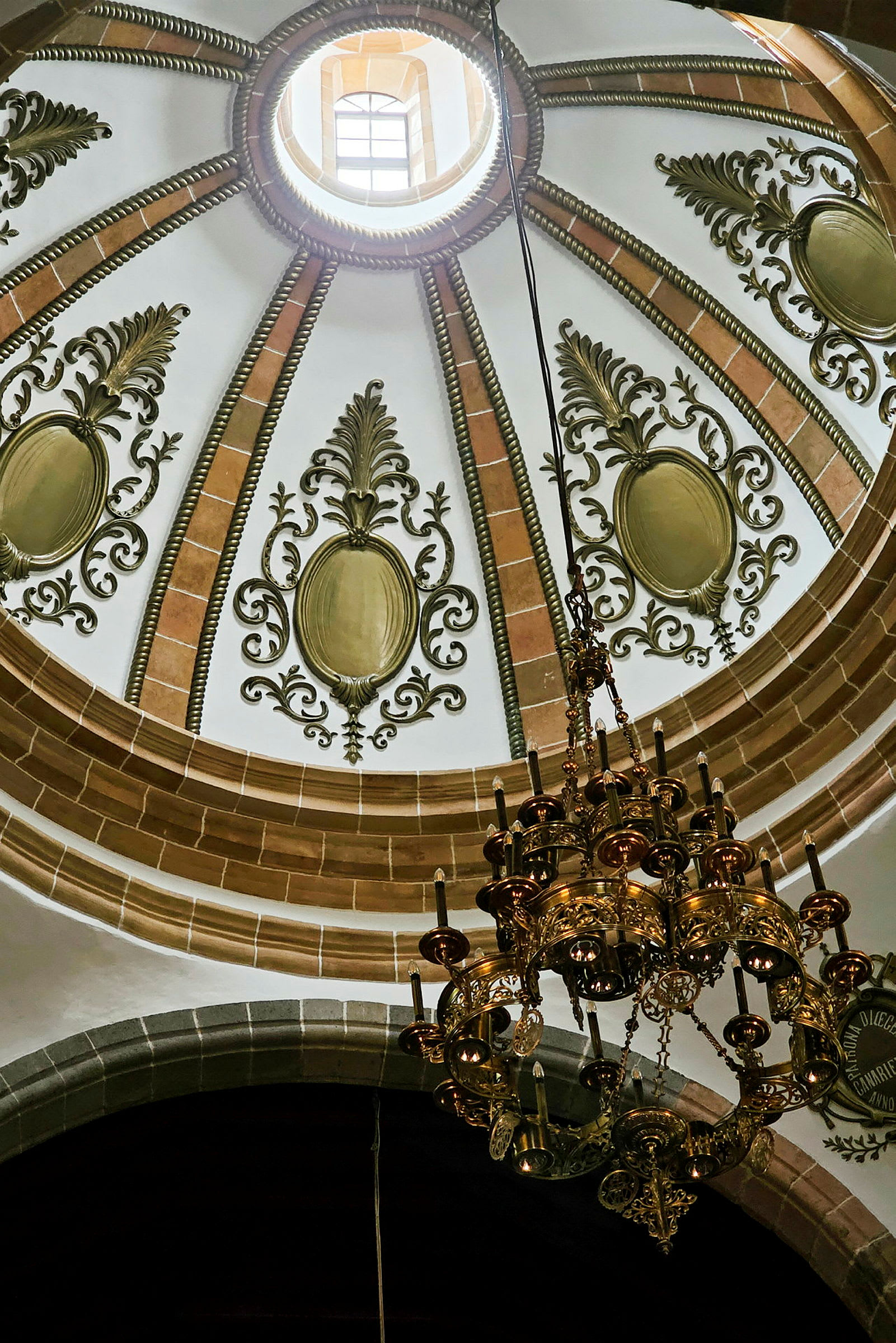 Interiøret av en kuppel med ornamentert takdekorasjon og en lysekrone. (AI-generert tekst)