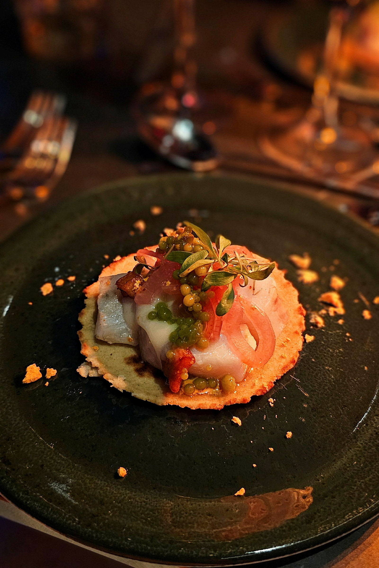 En tallerken med en gourmet-forrett bestående av tynt brød med fisk, grønnsaker og urter. (AI-generert tekst)
