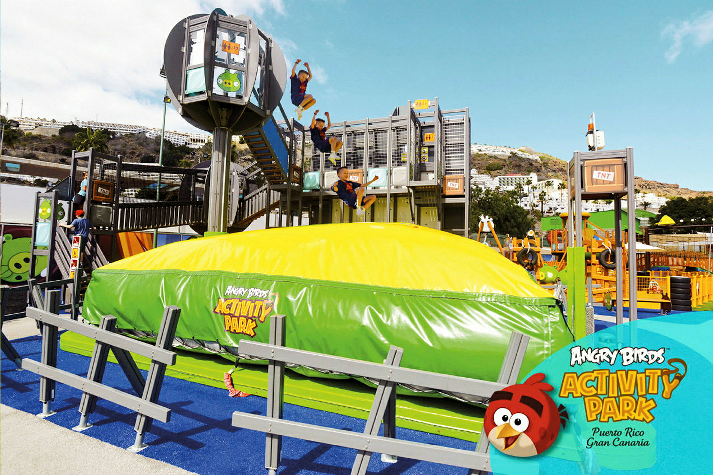 Et utendørs aktivitetsområde ved Angry Birds Activity Park med en stor oppblåsbar pute og flere lekestrukturer. (AI-generert tekst)