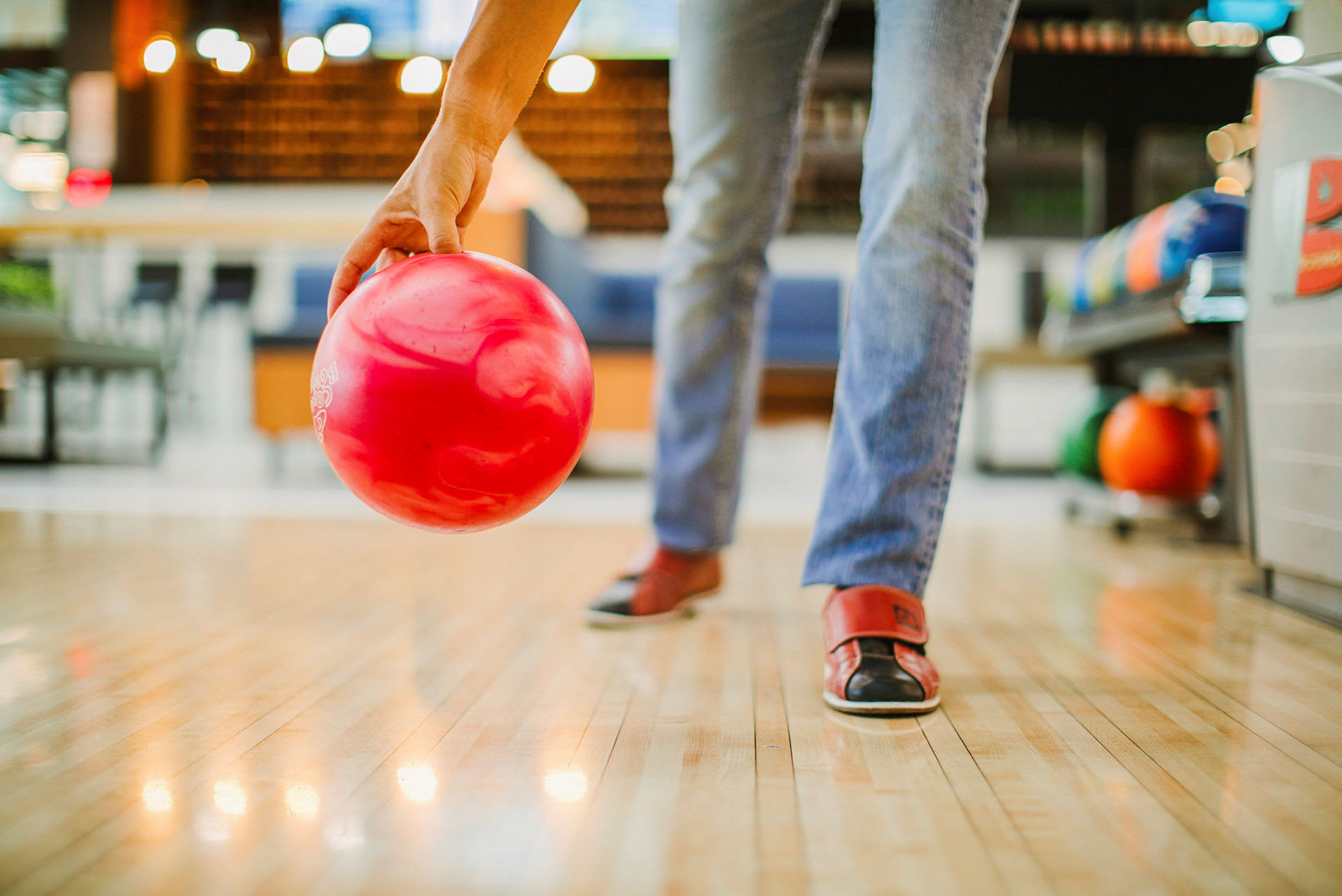 En person forbereder seg på å kaste en rød bowlingball på en bane. (AI-generert tekst)