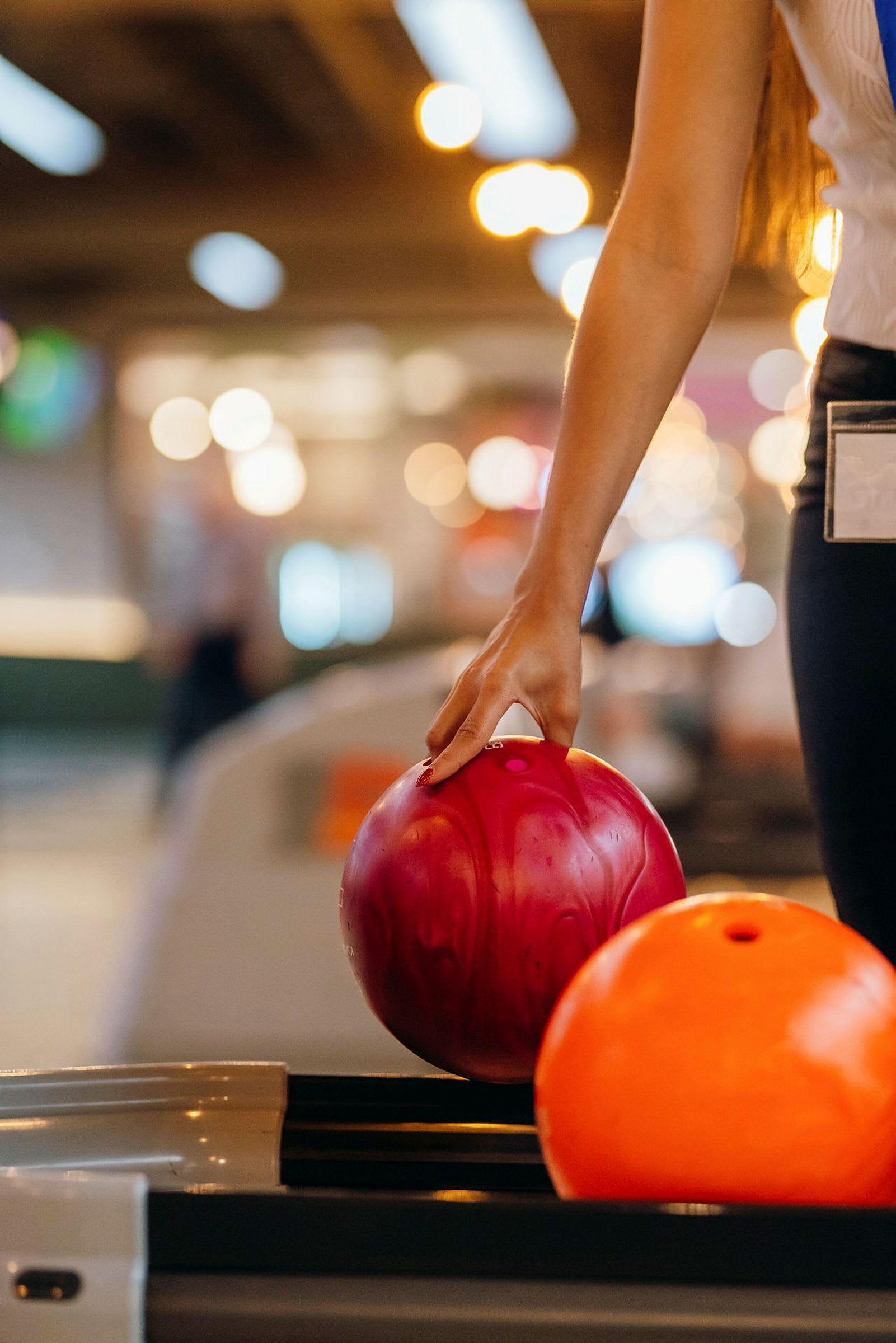 En person holder en rosa bowlingkule med hånden. (AI-generert tekst)