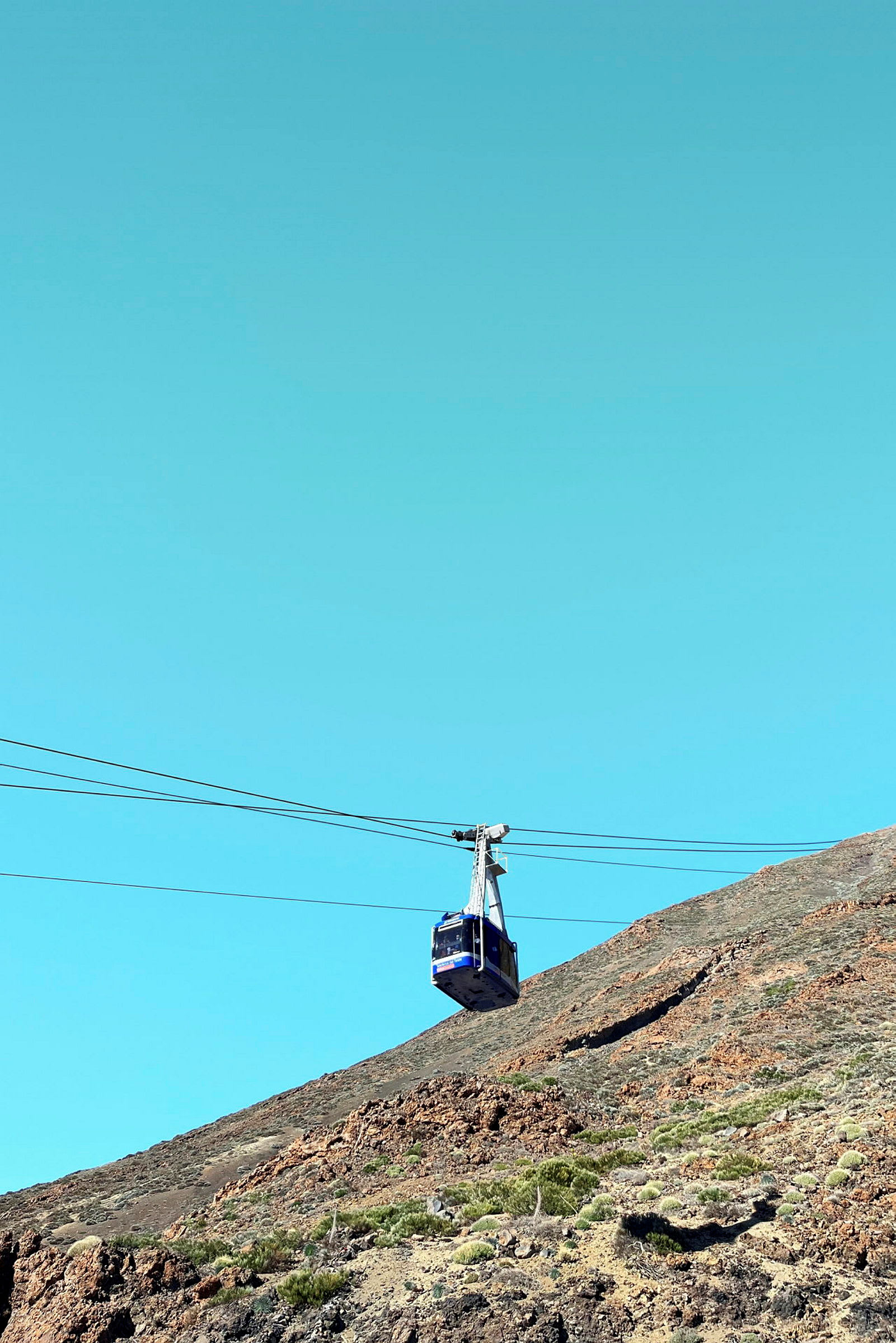En blå taubane over en fjellside med klar blå himmel. (AI-generert tekst)