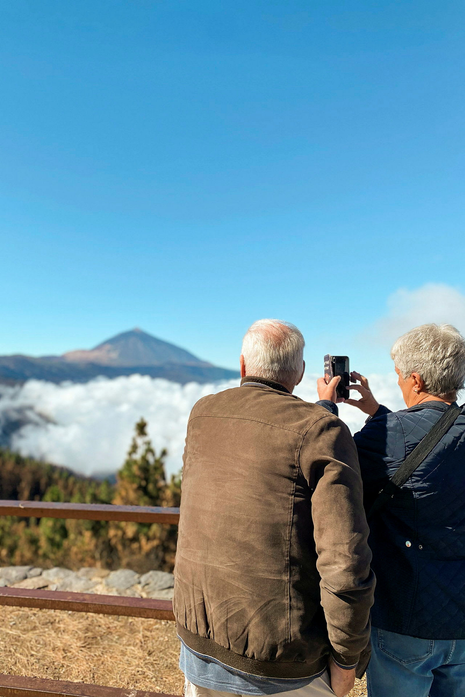 To personer fotograferer utsikten med fjell og skyer. (AI-generert tekst)