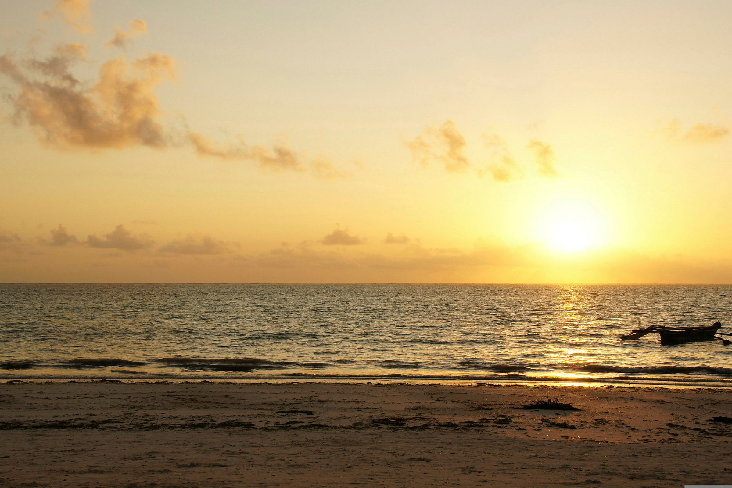 En strand med bølger og en solnedgang i bakgrunnen. (AI-generert tekst)