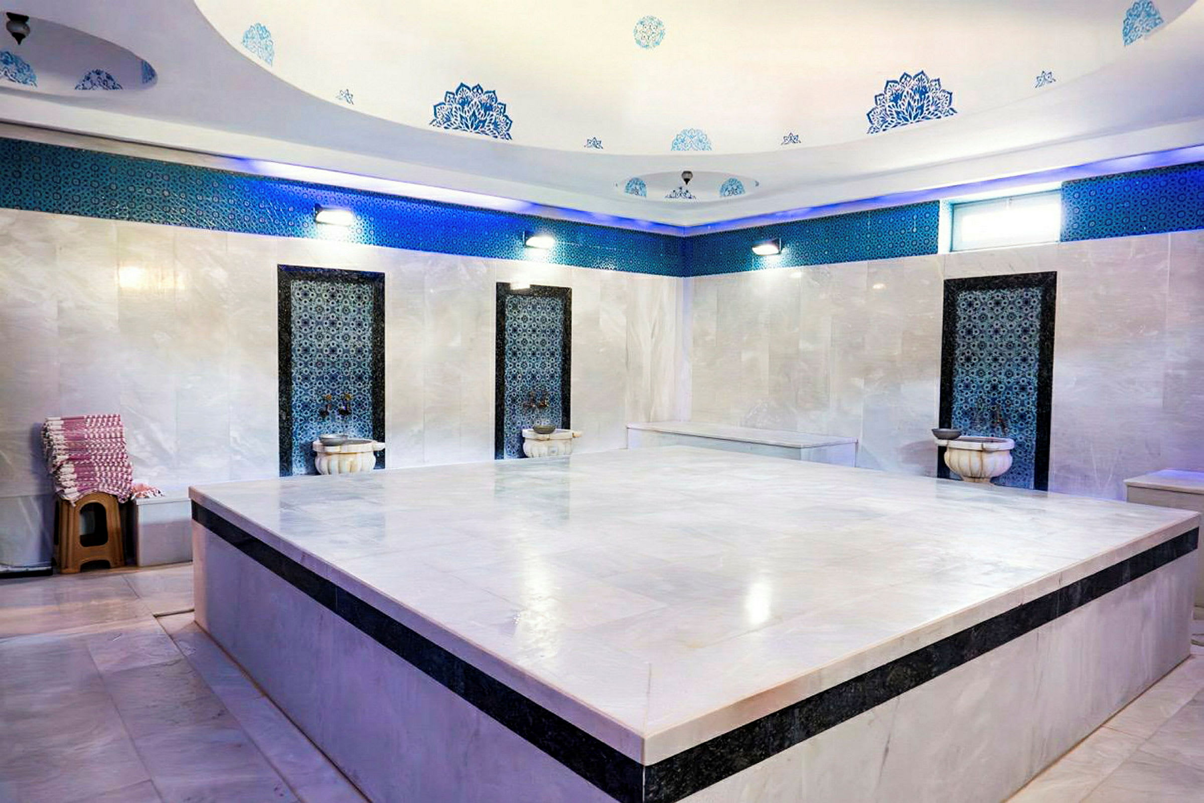 Et tradisjonelt tyrkisk hamam med marmorsvegger, dekorative detaljer og en stor sentral plattform. (AI-generert tekst)