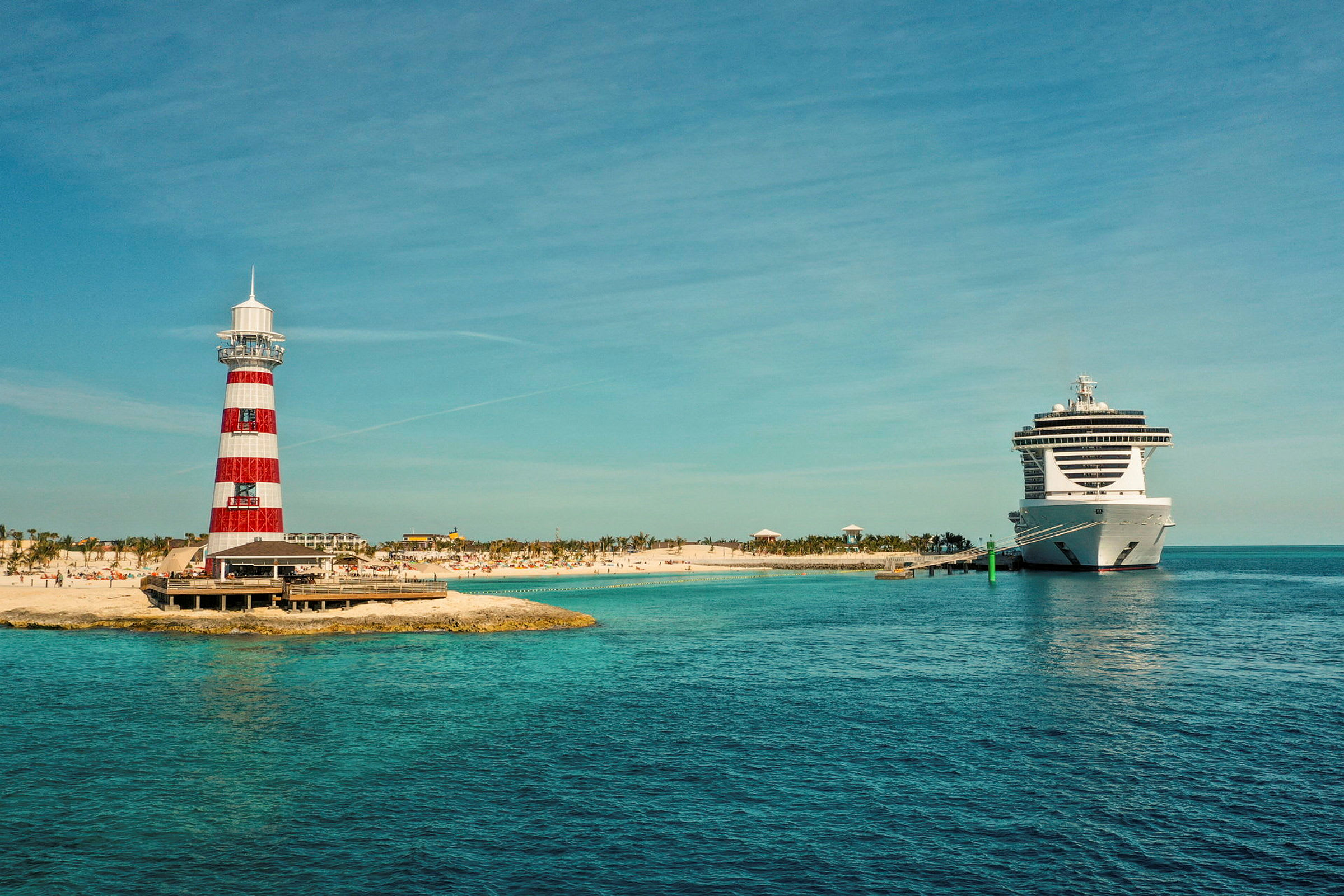 Et fyrtårn med røde og hvite striper står ved siden av et cruiseskip ved havet. (AI-generert tekst)